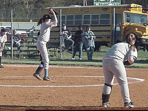 Rebekah Hobbs watching on first, Jennifer Nelson pitching, and Amy Crawford ready on third.