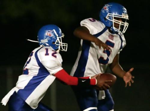 McGavock's quarterback Dominique Norman , #12, hands the ball off to John Crenshaw, #5.